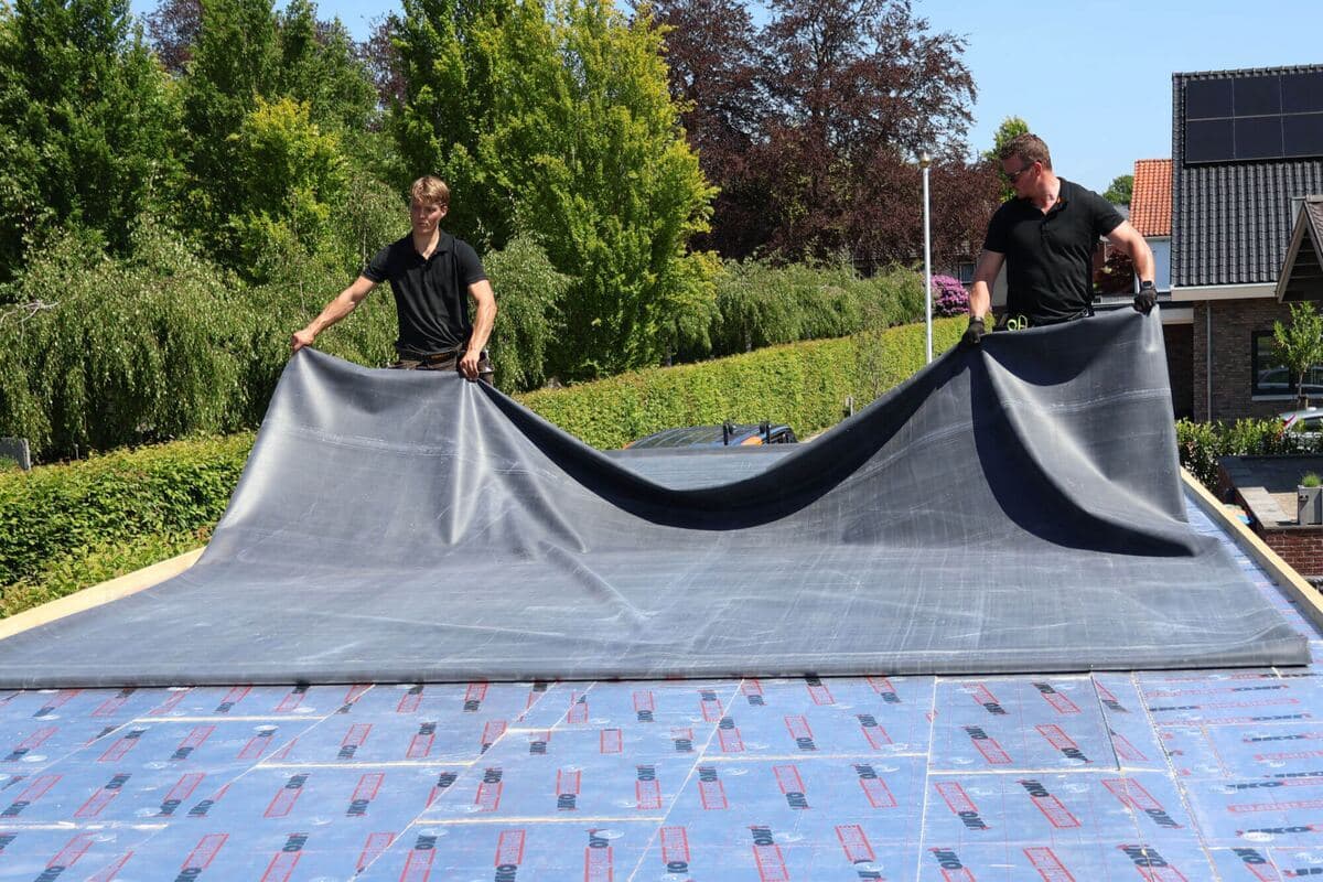 Twee dakdekkers leggen een EPDM-folie op een geïsoleerd dak